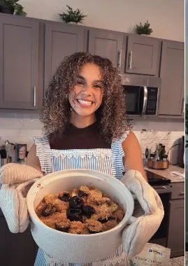 A Prunefluencer holding a baked prune dish in her kitchen
