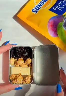 A snack tin packed with prunes, nuts and cheese